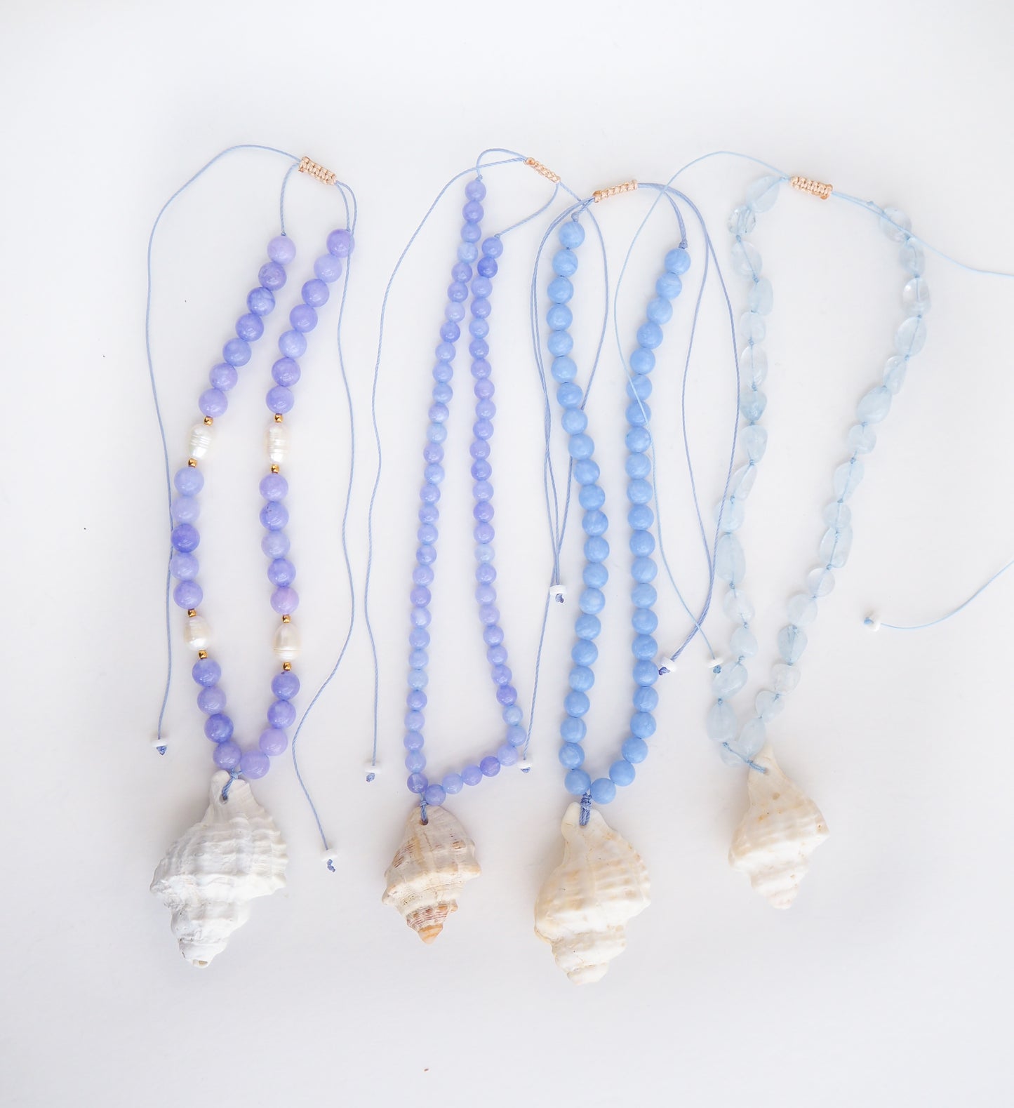 A collection of 4 Big Shell Necklaces with Gemstone Beads on display, Blue gemstone bead necklace with off white big conch shell, Handpicked shells from Portugal