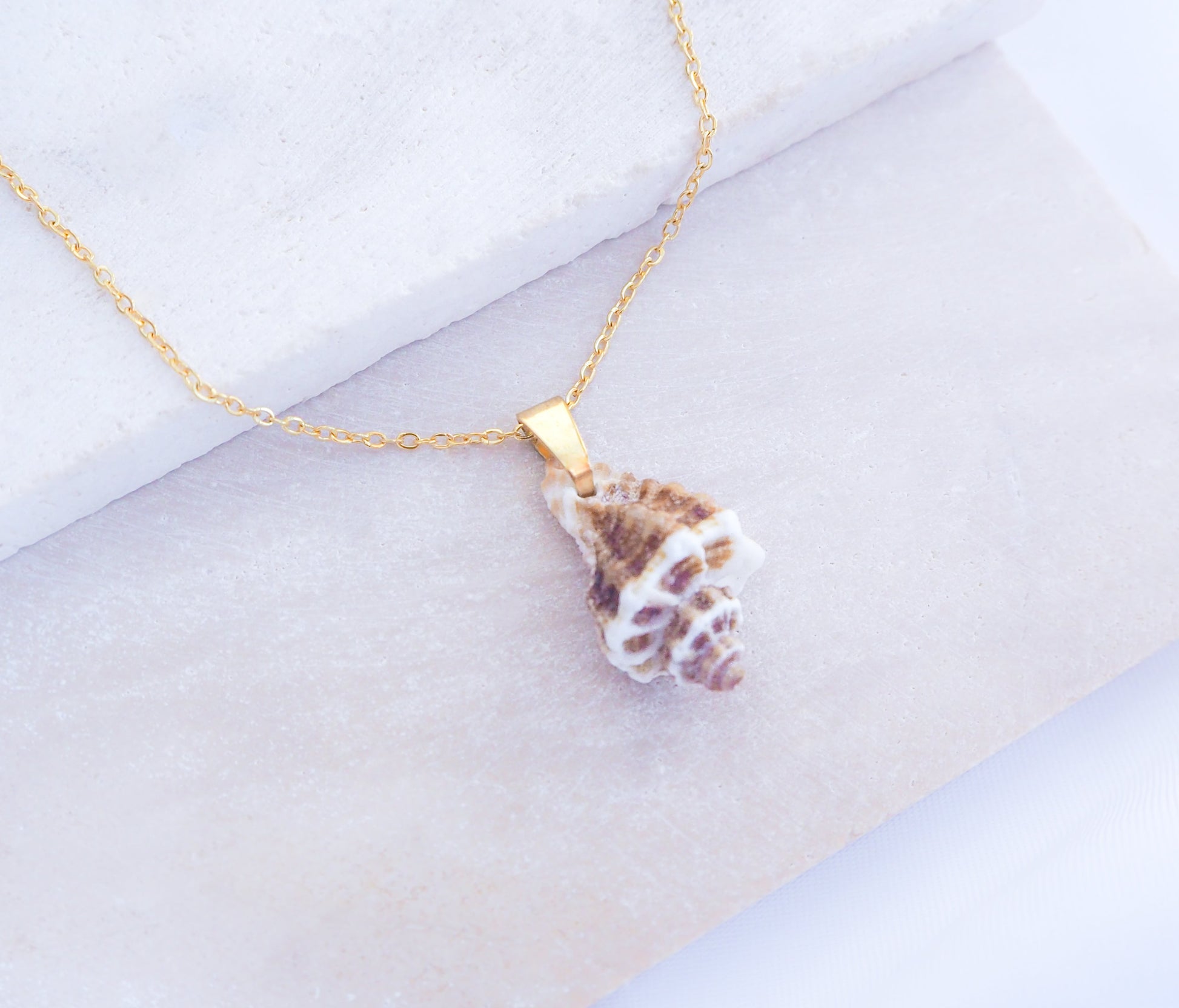 Brown White Sting Winkle Gold Necklace on display