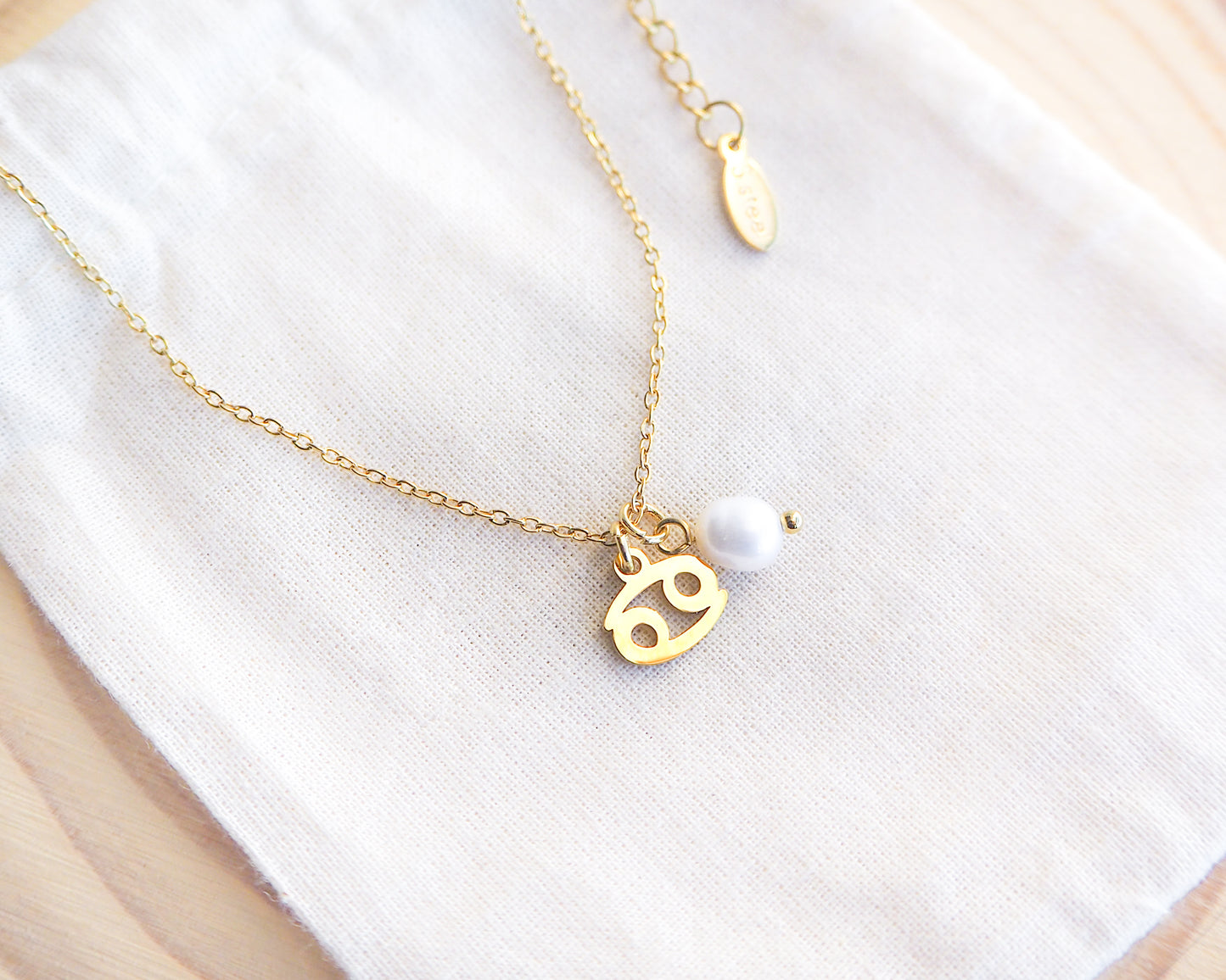 Gold Cancer Zodiac Pearl Necklace on display, made with 18k gold stainless steel and white freshwater pearl