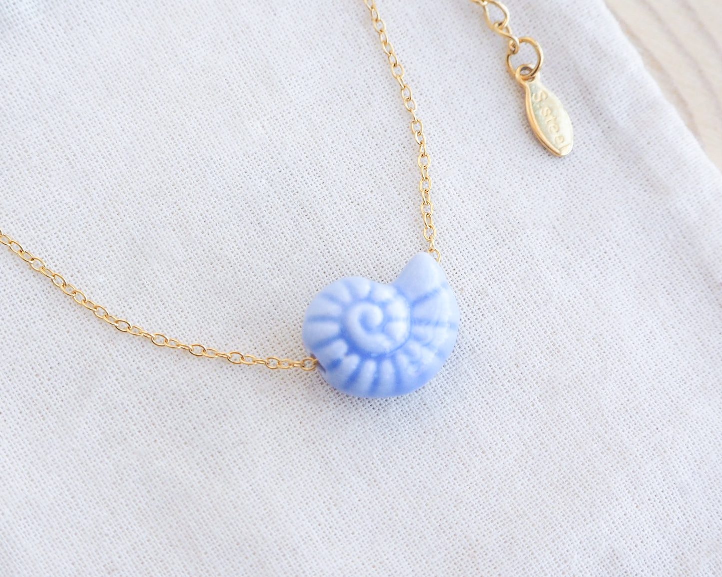 Blue Ceramic Seashell Nautilus Gold Necklace on display