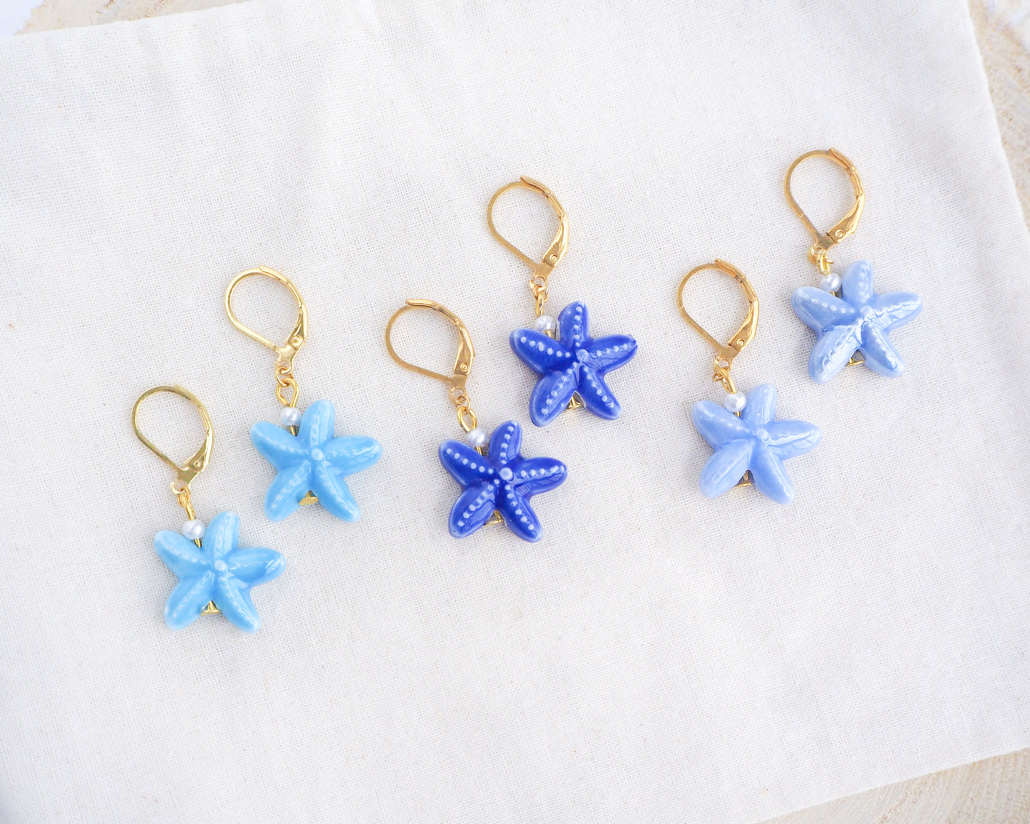 Ceramic Blue Starfish Sea Star Gold Earrings on display