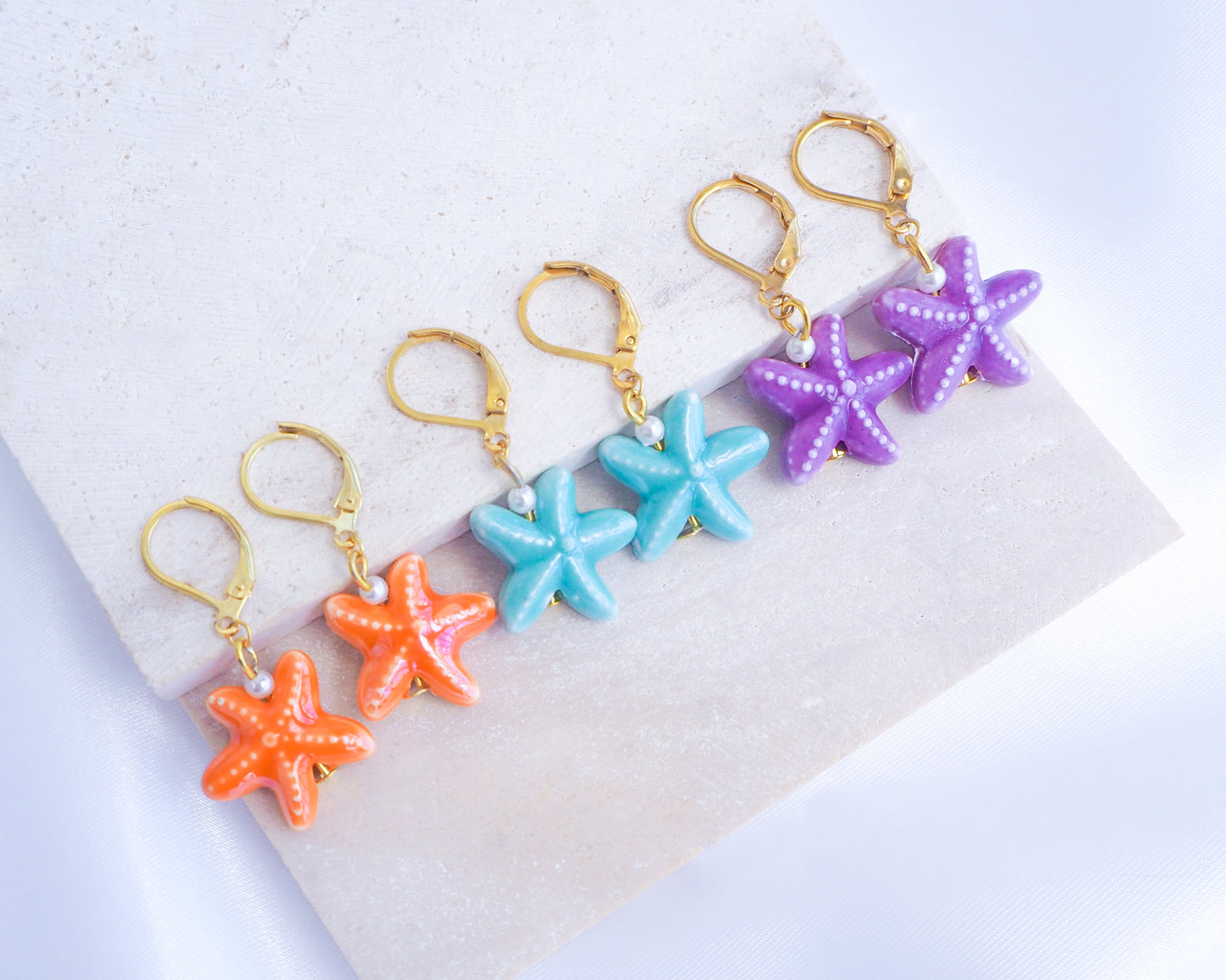 Mix of Ceramic Sea Star Gold Earrings on stone display