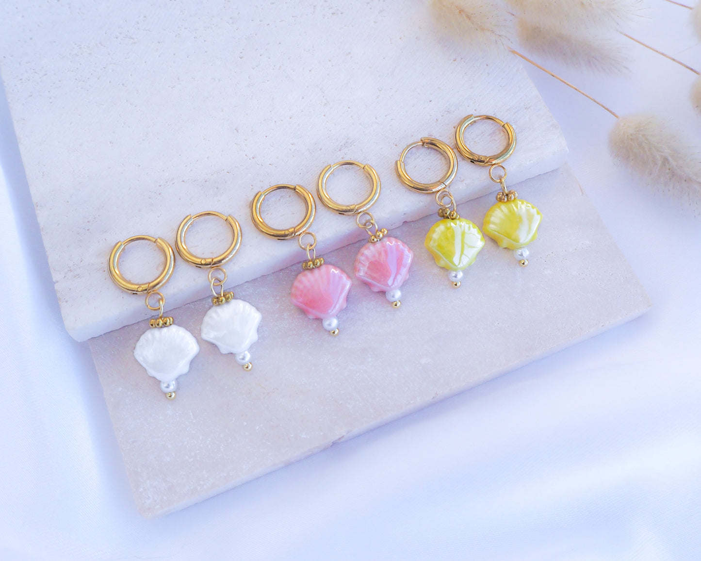 Ceramic Shell Gold Earrings with yellow, white or pink shell pendants on display