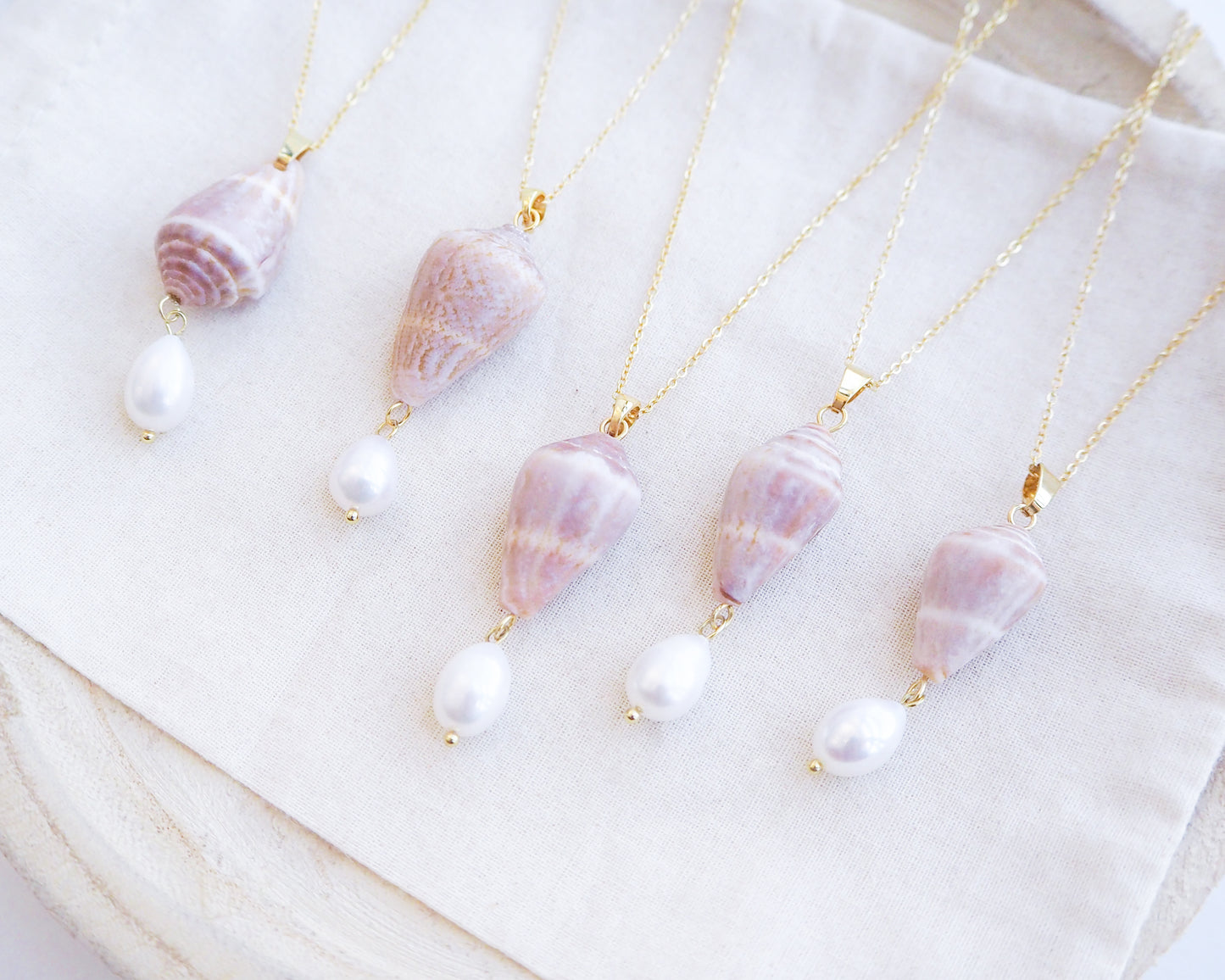 Side view of Mediterranean Cone Shell Pearl Necklace Reversed from Portugal displayed, handpicked cone shell from Algarve, Freshwater pearl and 18k gold stainless steel chain