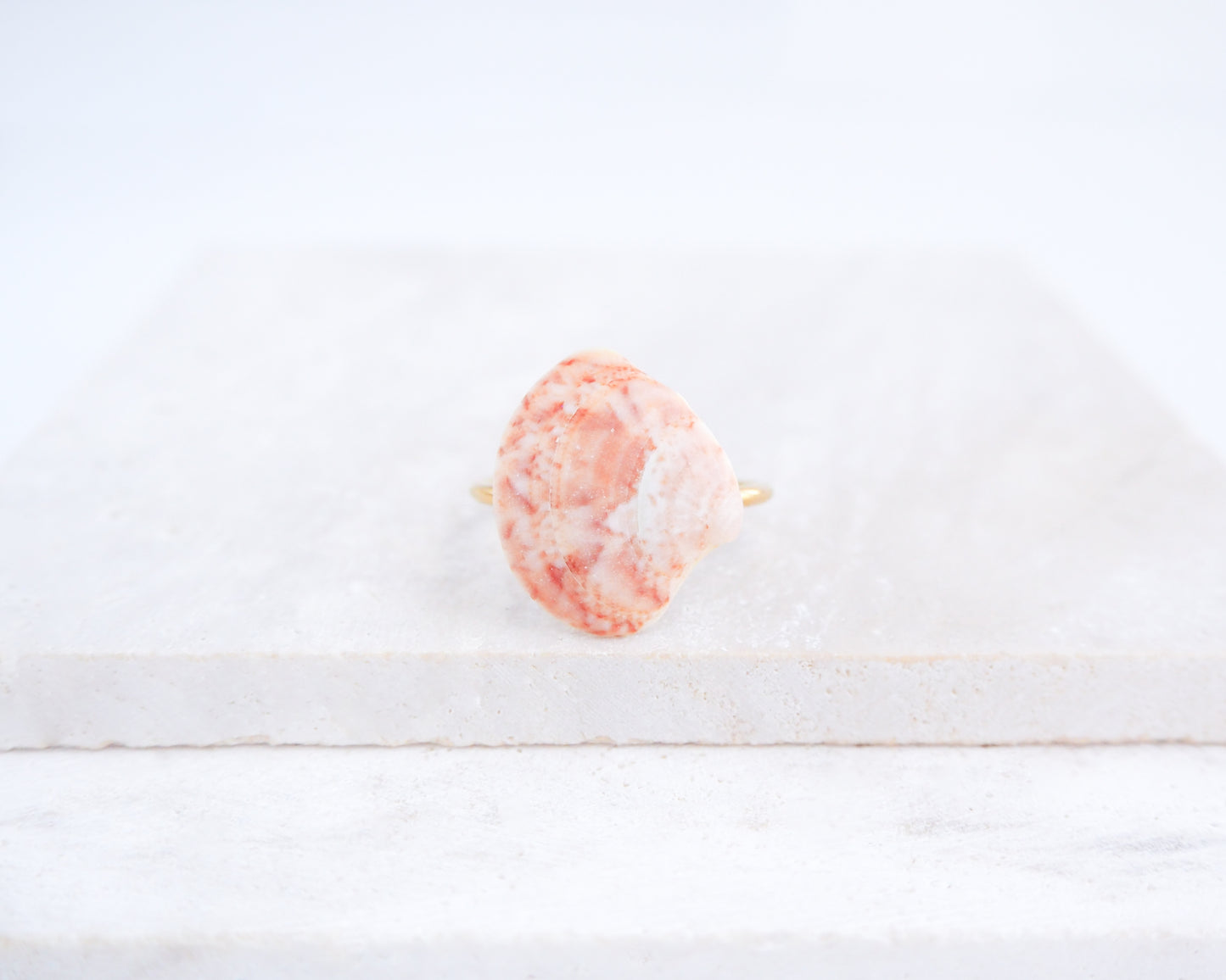 Close up of Coral Pink Venus Shell Ring from Portugal displayed on stone, Marble Pink shell on gold ring, handpicked real shell from Portugal