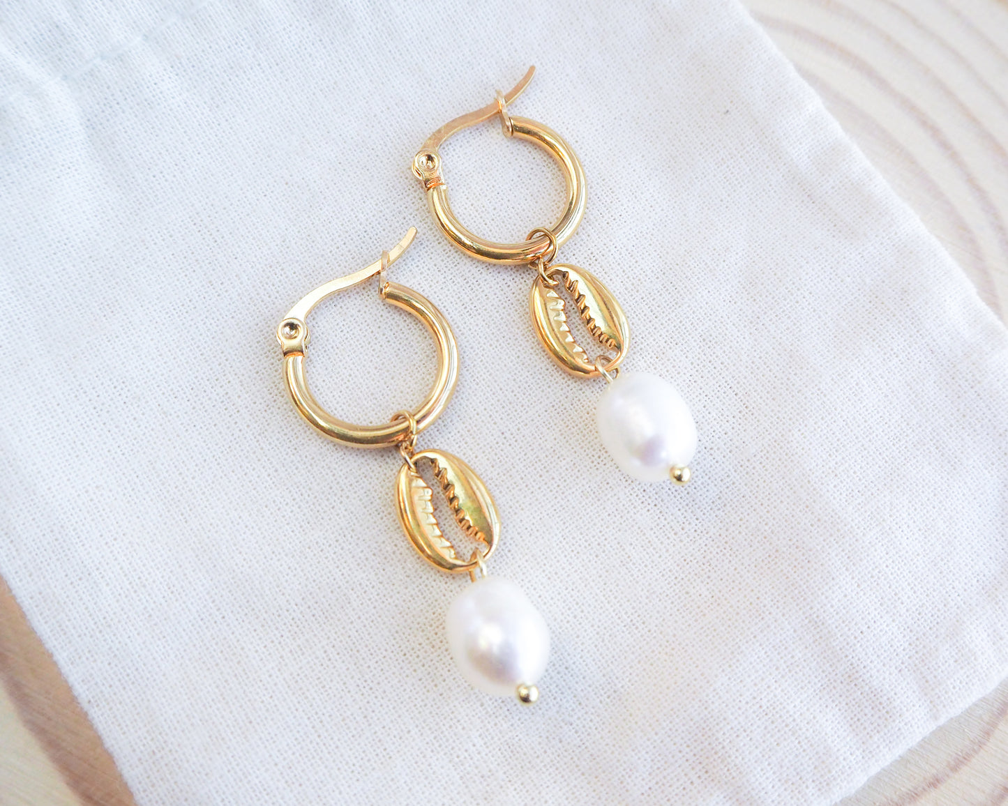 Gold cowrie shell earrings with freshwater pearls on displayed