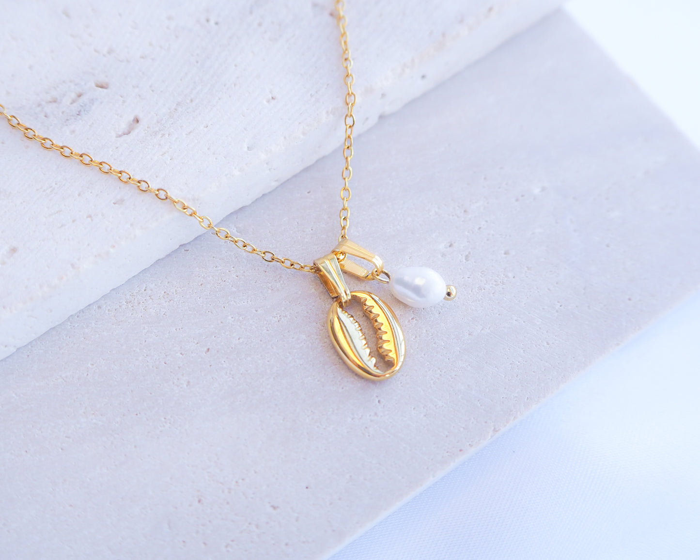 Gold Cowrie Shell Necklace with Pearl on display
