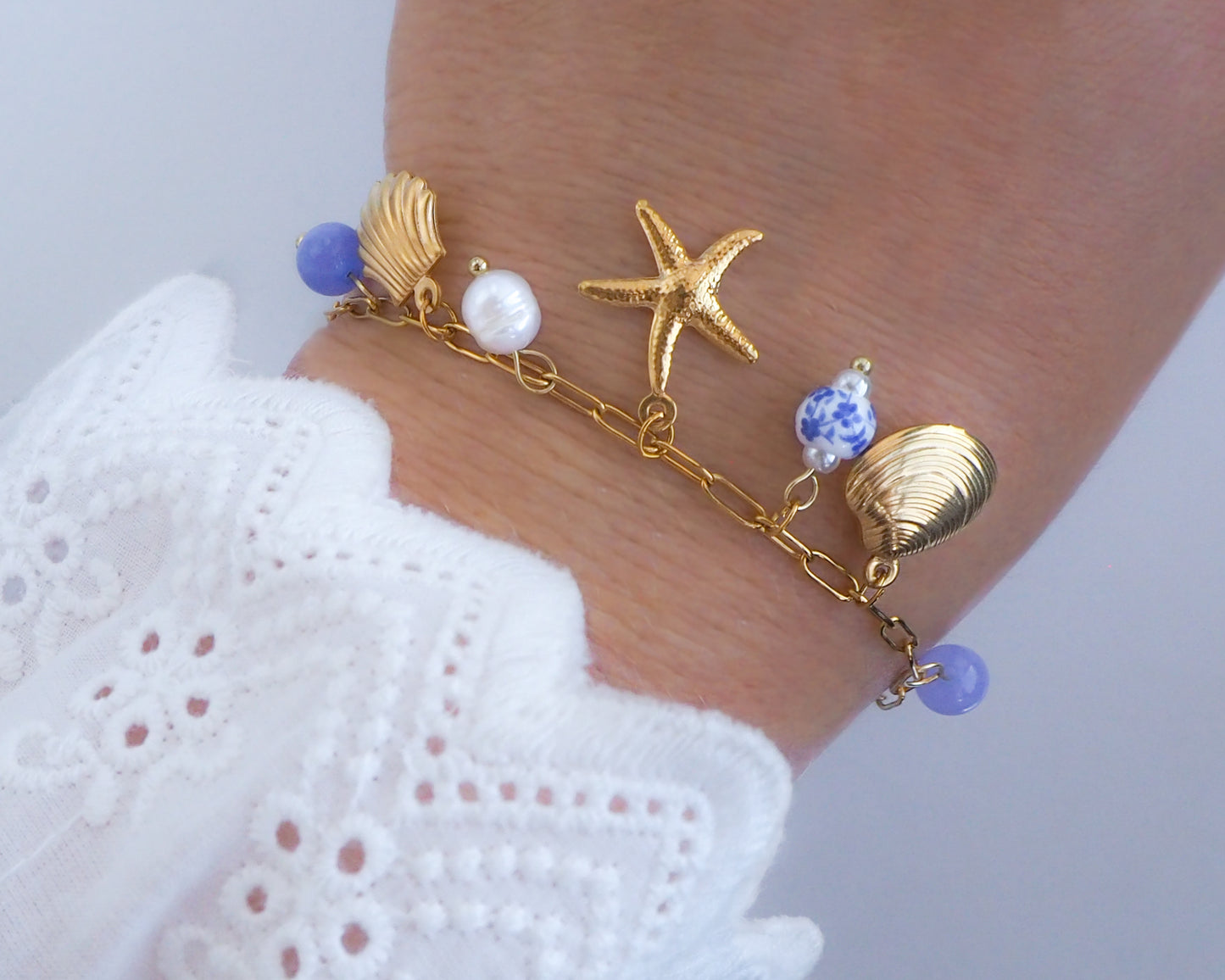 Gold Oceanic Charm Bracelet on wrist, made with azulejo ceramic beads, gemstones and starfish sea star shell pendants