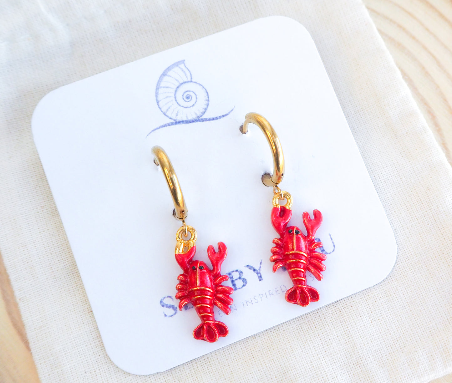 Gold Red Lobster Hoop Earrings on display