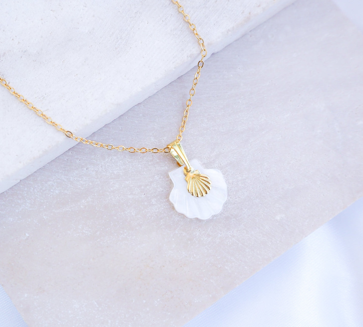 Gold Shell Mother of Pearl Necklace on stone displayed, made with mother of pearl pendants and a dainty tiny gold shell.