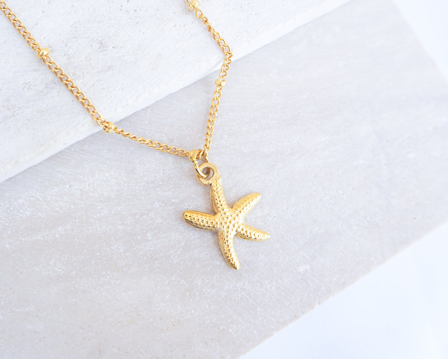 Gold starfish sea star necklace on a white background