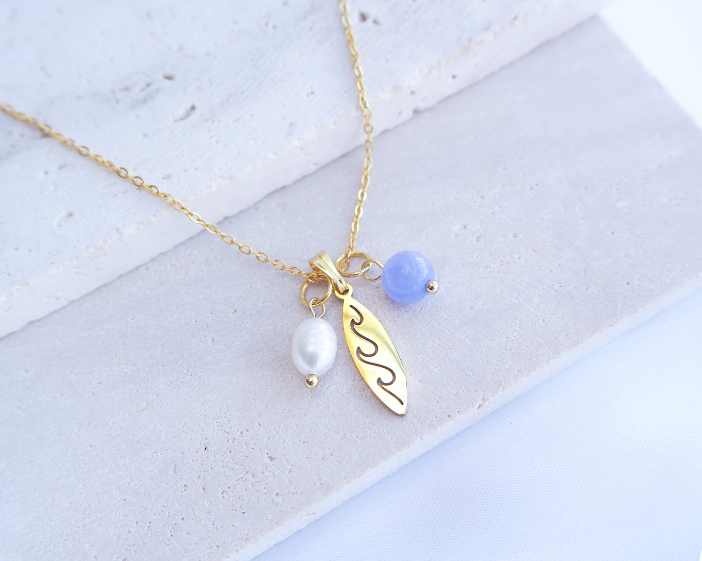 Gold Surfboard Necklace with Freshwater Pearl Angelite Beads on display
