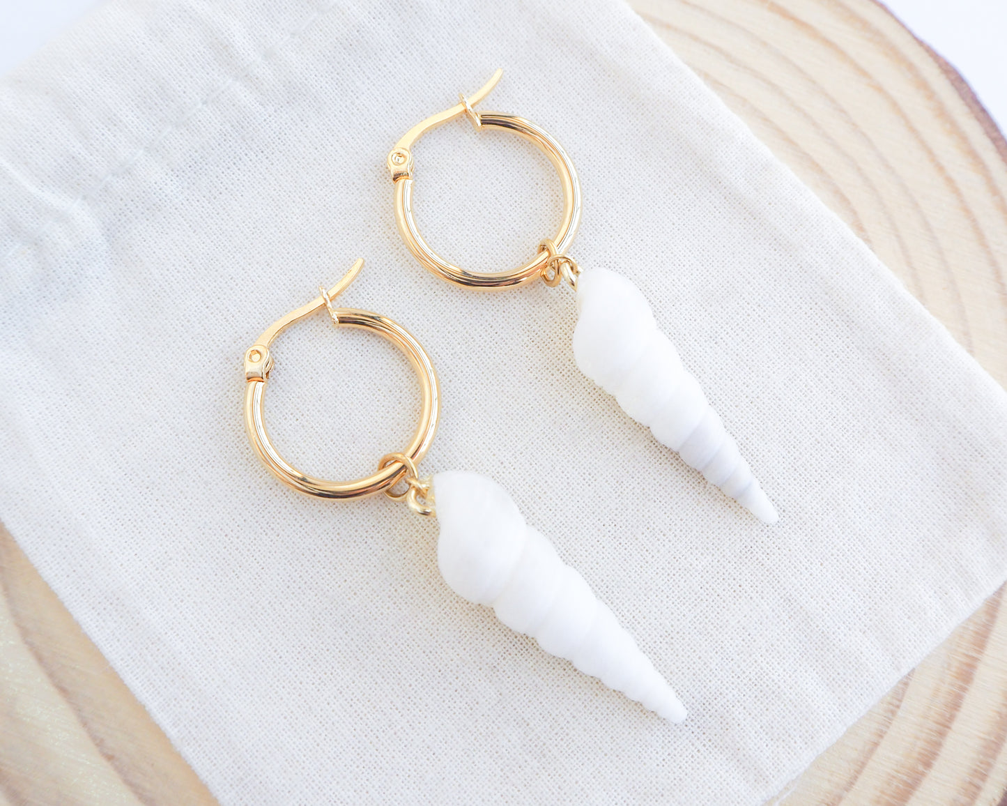 Close up of White Common Tower Shell Gold Earring Hoops on display, handpicked white tower shells from Portugal, 18k gold stainless steel shell earring hoops, seabylou