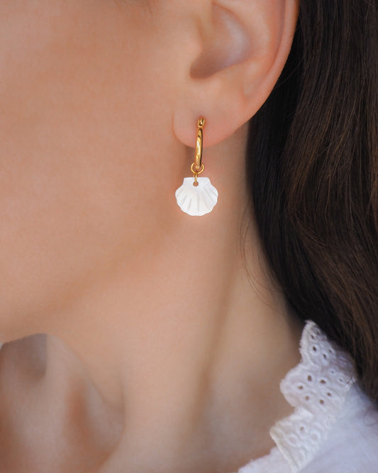 gold hoop earrings with mother-of-pearl shell pendants in ear model
