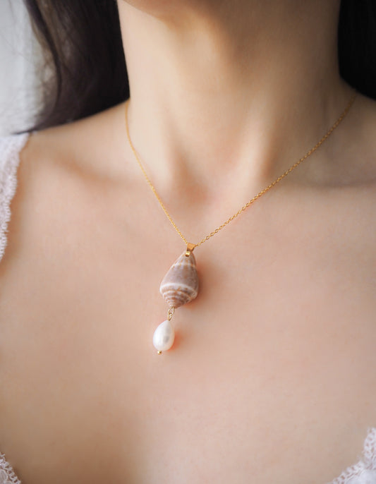 Model wearing Mediterranean Cone Shell Pearl Necklace Reversed II from Portugal on stone, handpicked cone shell from Algarve, Freshwater pearl and 18k gold stainless steel chain