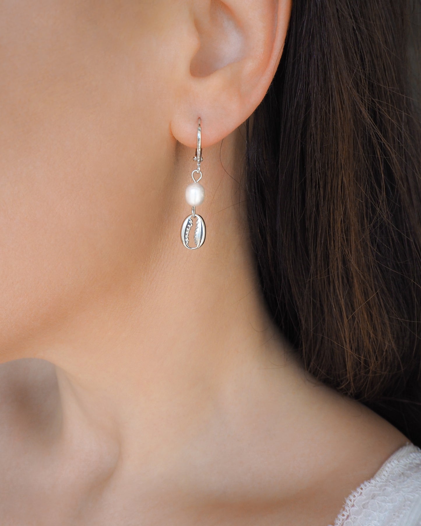 Model wearing Silver Hoop Earrings with Cowrie Shells and Freshwater Pearls in ear side view.