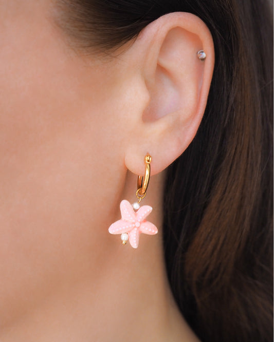 Soft Pink Ceramic Starfish Gold Earrings in ear model, 14k gold stainless steel hoops with pink ceramic sea star pendants