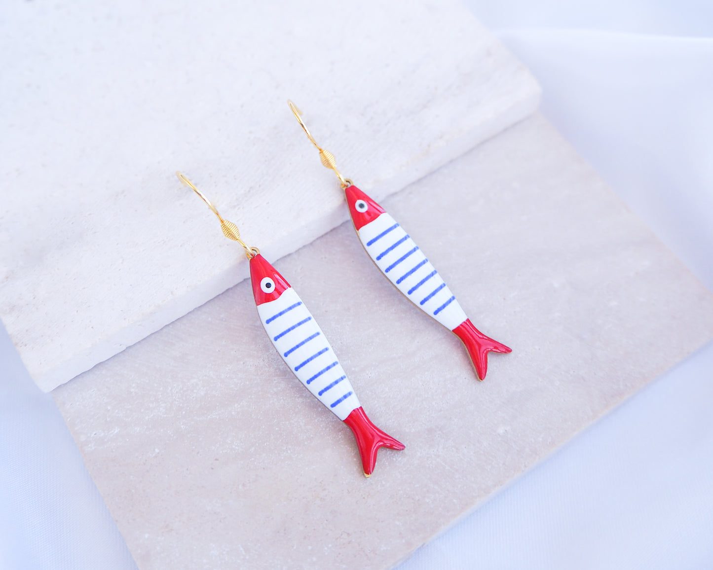 Nautical Striped Sardine Fish Earrings with 14k gold stainless steel earring hooks displayed on stone, Red Blue White Striped Fish Pendant, Beautiful gift for Portugal lovers or holiday memory, coastal jewelry from Portugal