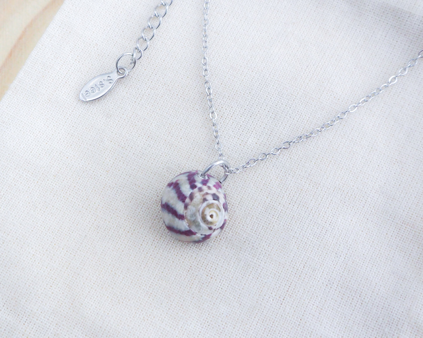 Purple Striped Top Shell Silver Necklace on display