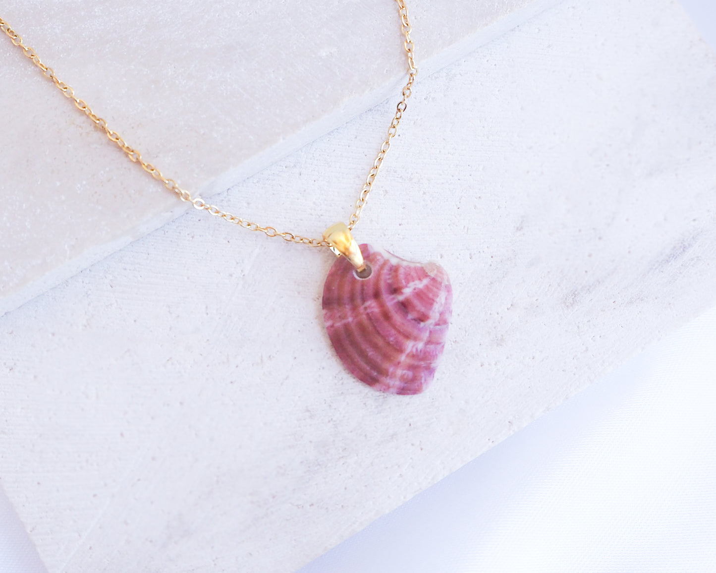 Raspberry Fuchsia Venus Shell Gold Necklace on stone displayed