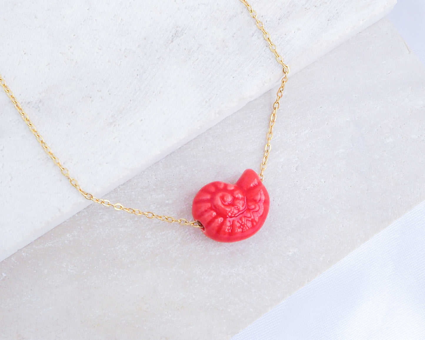 Red Seashell Ceramic Nautilus Gold Necklaces on stone displayed