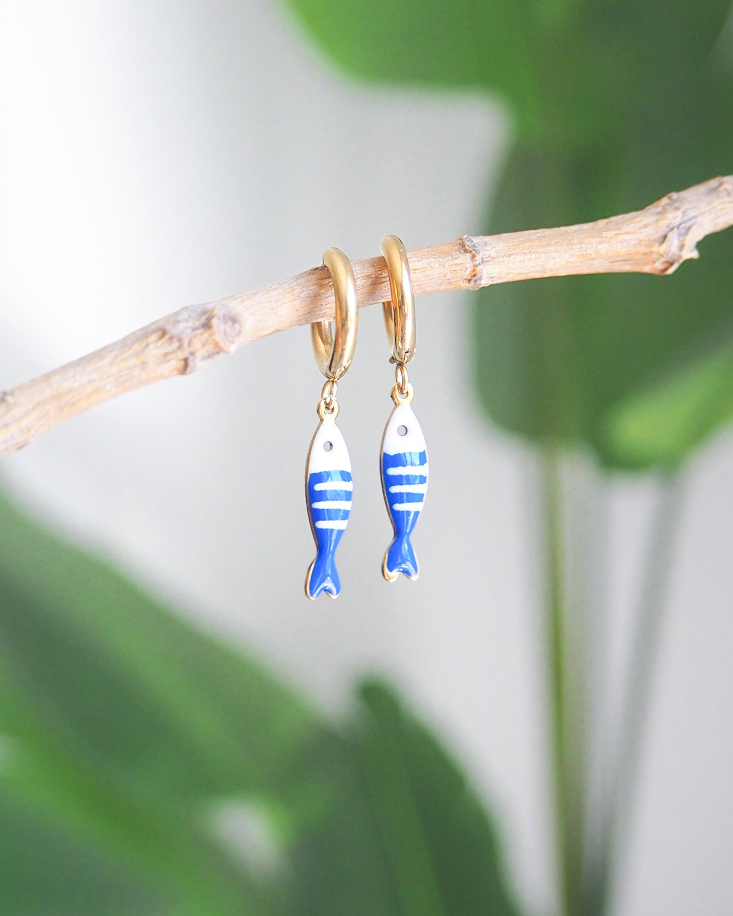 Tiny sardine fish hoop earrings with green plant background. The fish pendant is blue and white striped. Made with 18k gold stainless steel earring hoops. Beautiful gift for Portugal lovers or holiday memory, coastal jewelry from Portugal. Nautical minimalistic jewelry