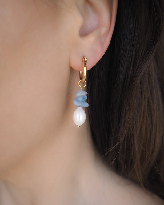 Model wearing gold hoop earrings in ear. Made with 14k gold stainless steel, aquamarine gemstone beads and freshwater pearls.