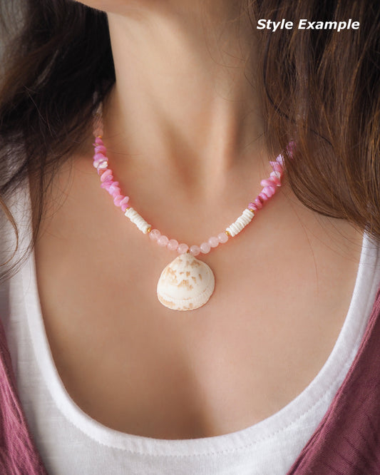 Necklace with pink and white beads and a shell pendant on a person wearing a white top. Model wearing a necklace with a big white cockle shell paired with rose quartz gemstone beads, soft pink stones and white shell beads. The shell is a Norwegian cockle shell handpicked from Portugal and is about 4 cm. The color of the shell is ivory white with a beige brown pattern.