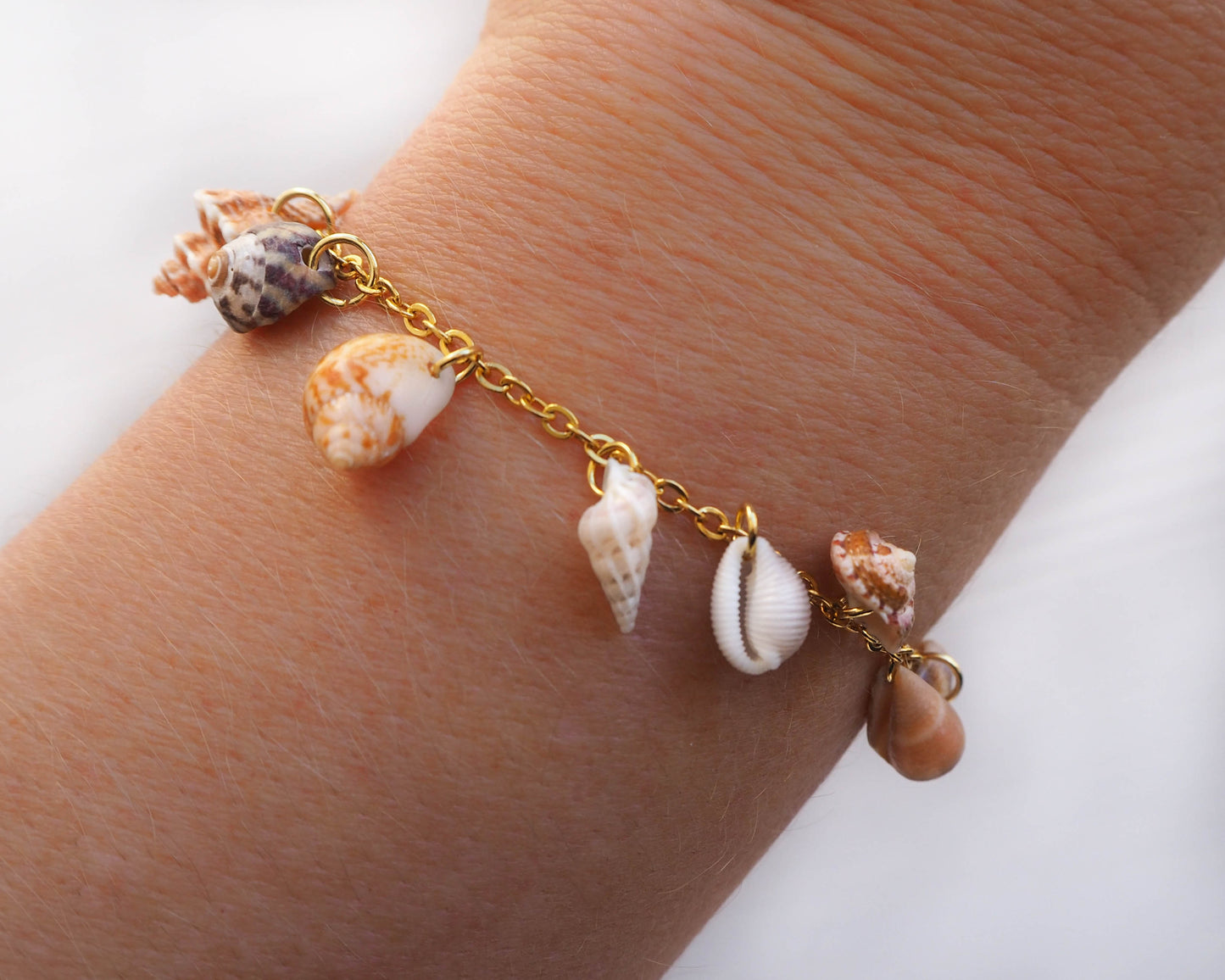 Model wearing Shell Jewelry from Portugal, Coastal Charm Collection: 8 Tiny Shells on Gold Stainless Steel - Mediterranean Cone, European Cowrie, Flat Topshell, Rustic Dove, Common Wentletrap, Sting Winkle, European Painted Topshell, Nassa Mud Shell
