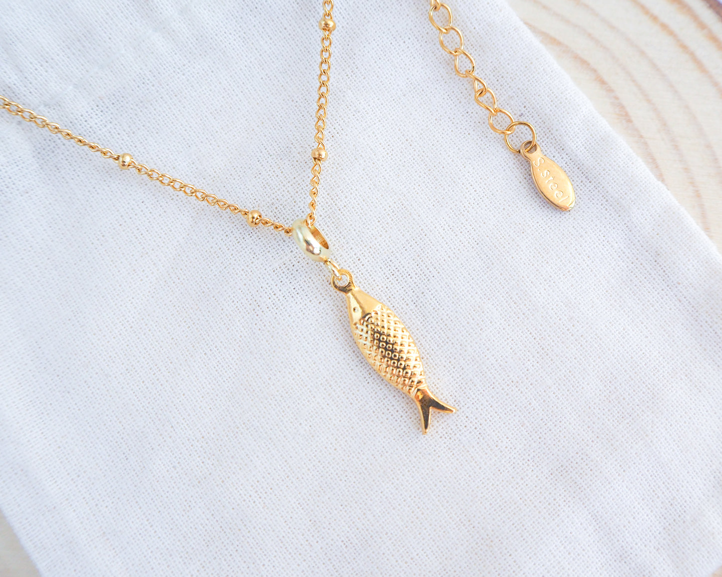 Close up of Gold Sardine Fish Necklace From Portugal on light cotton displayed.