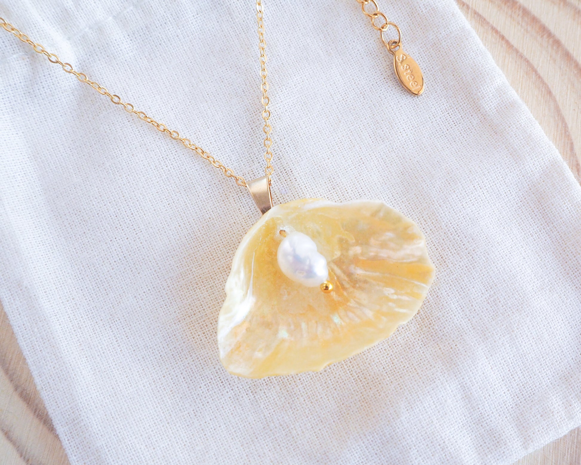 Soft Yellow Jingle Shell Gold Necklace on display, Mother of Pearl Pendant