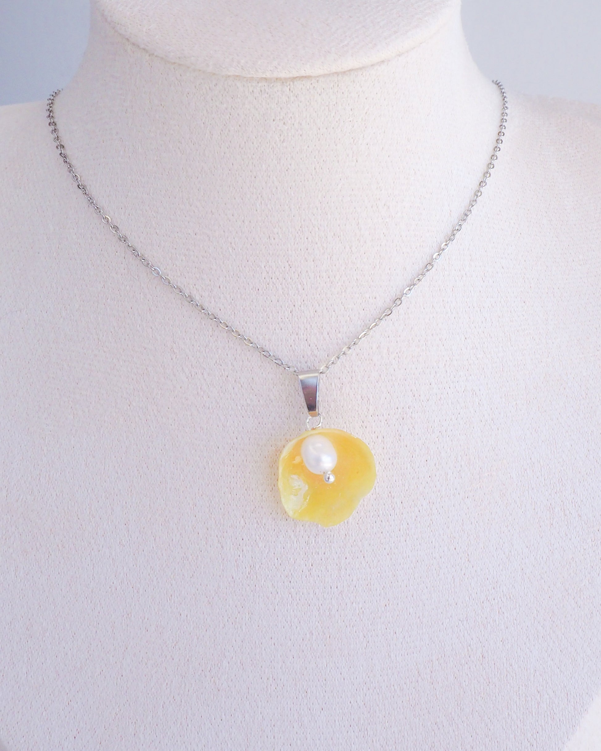 Yellow Jingle Shell Silver Necklace on display, Mother of Pearl Pendant