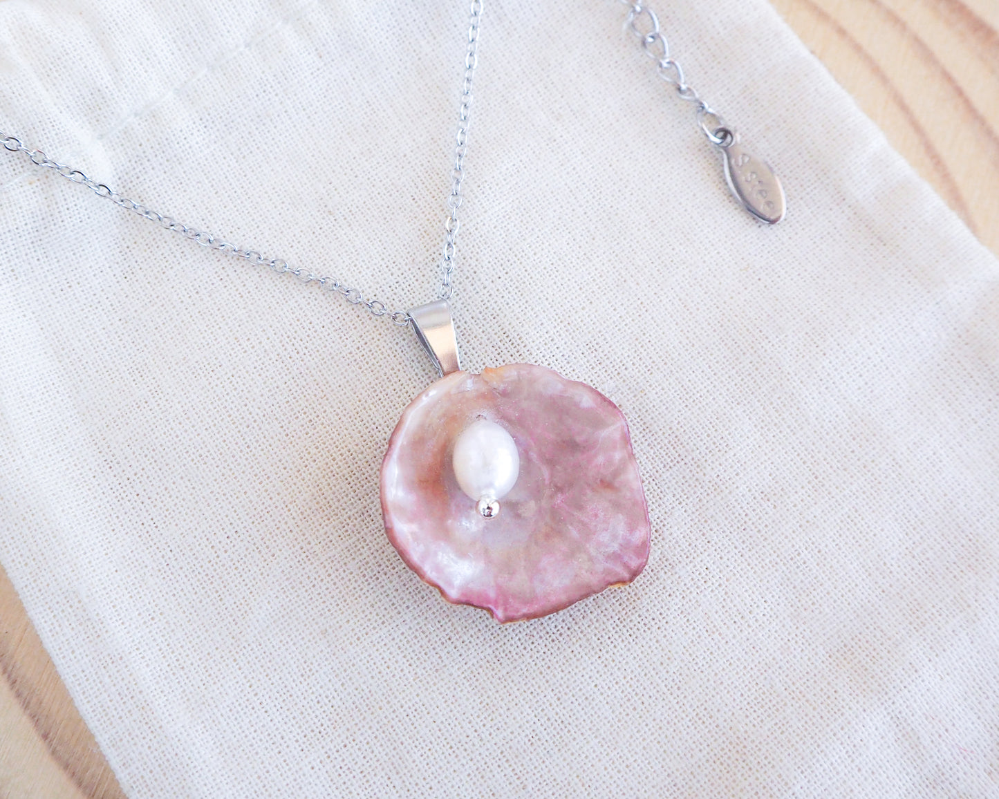 Pink Jingle Shell Silver Necklace with Freshwater Pearl on display