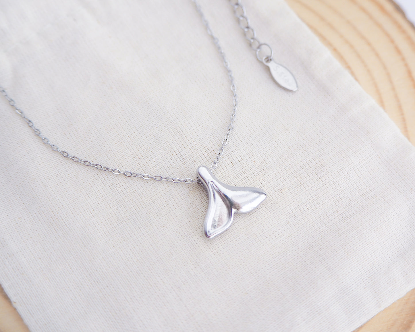 Silver whale tail necklace on a white background. Made with silver stainless steel. Beach summer jewelry