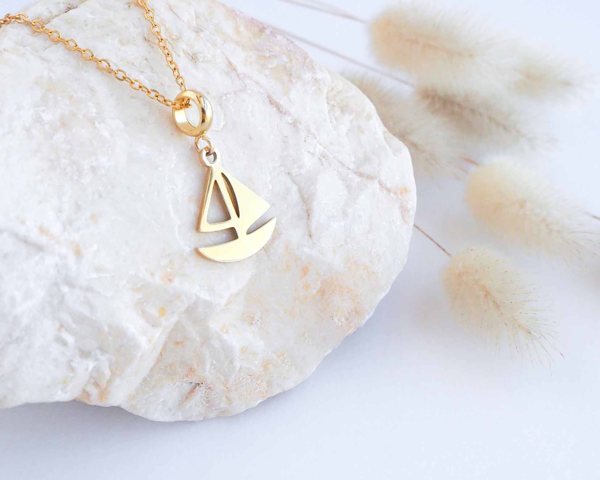 Gold Sailing Boat Necklace on stone