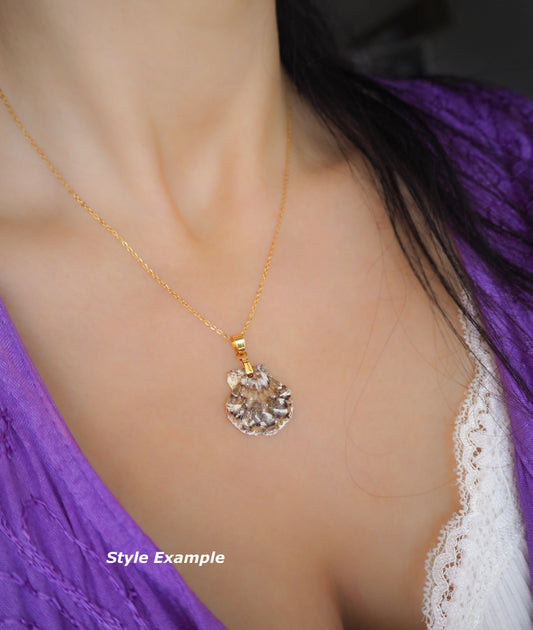 A gold chain necklace with a clear faceted shell-shaped pendant, worn by a model in a purple top. The image includes a 'Style Example' text overlay in the bottom left corner.