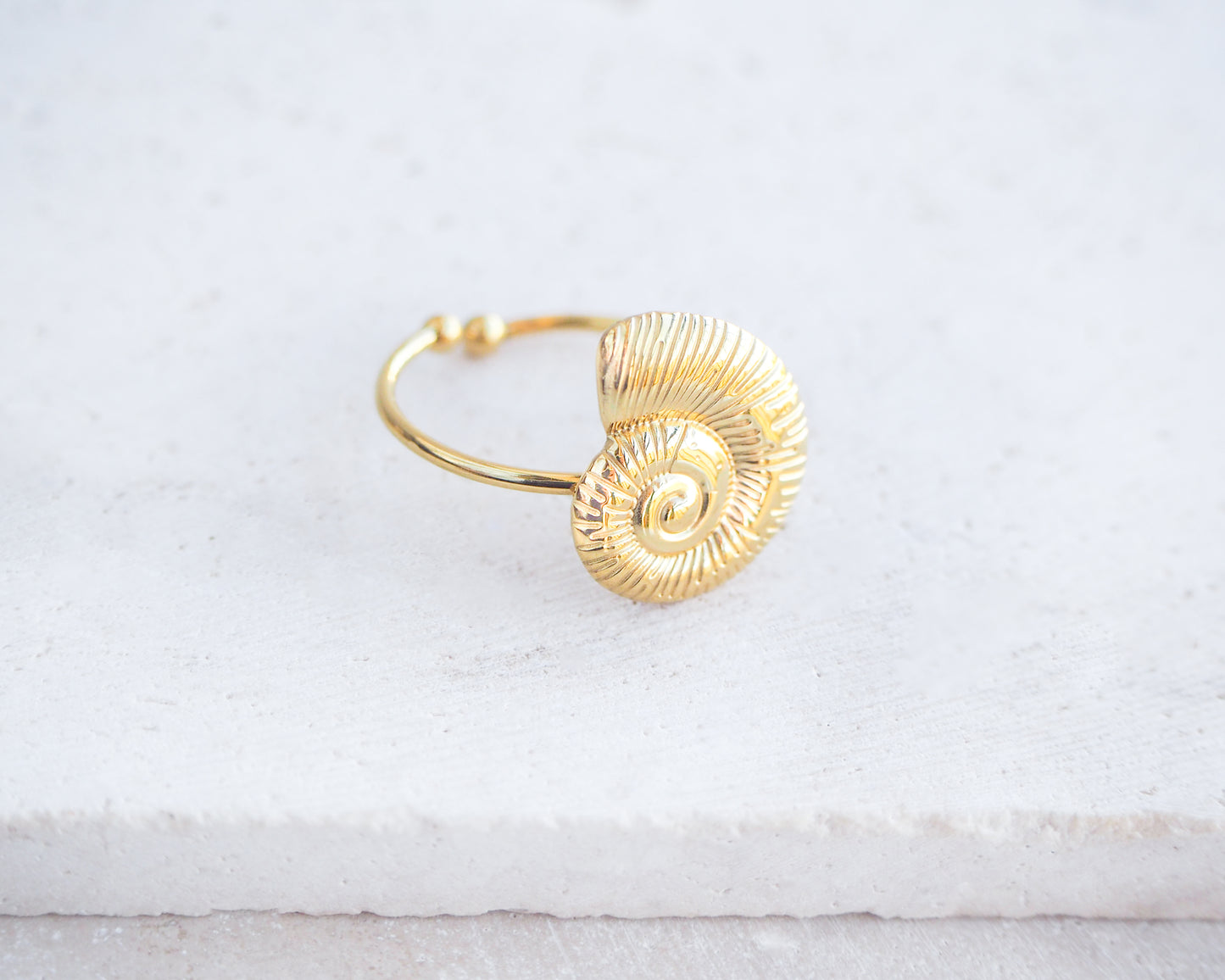 Side view of Gold Nautilus Seashell Ring on stone displayed, adjustable 18k gold stainless steel shell ring