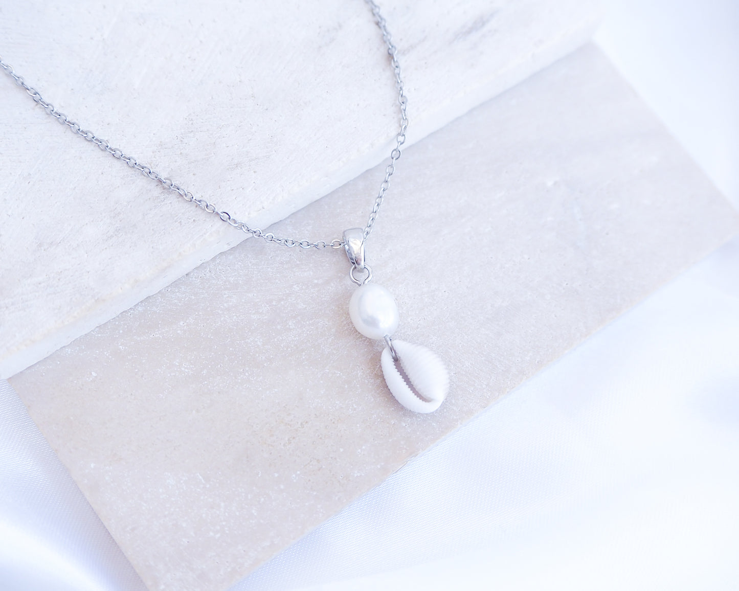 Silver Cowrie Shell Pearl Necklace Freshwater Pearl Pearl on stone displayed