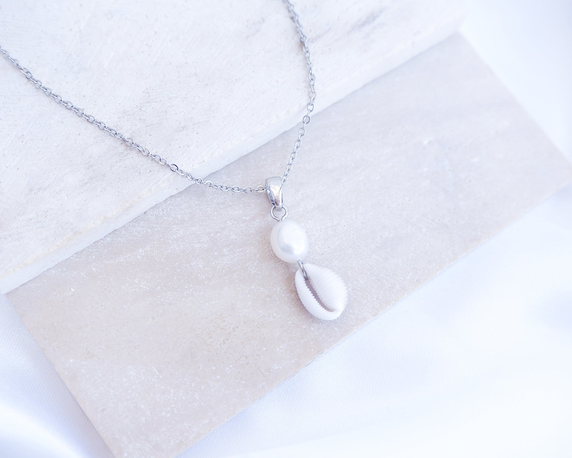 Silver Cowrie Shell Pearl Necklace Freshwater Pearl Pearl on stone displayed