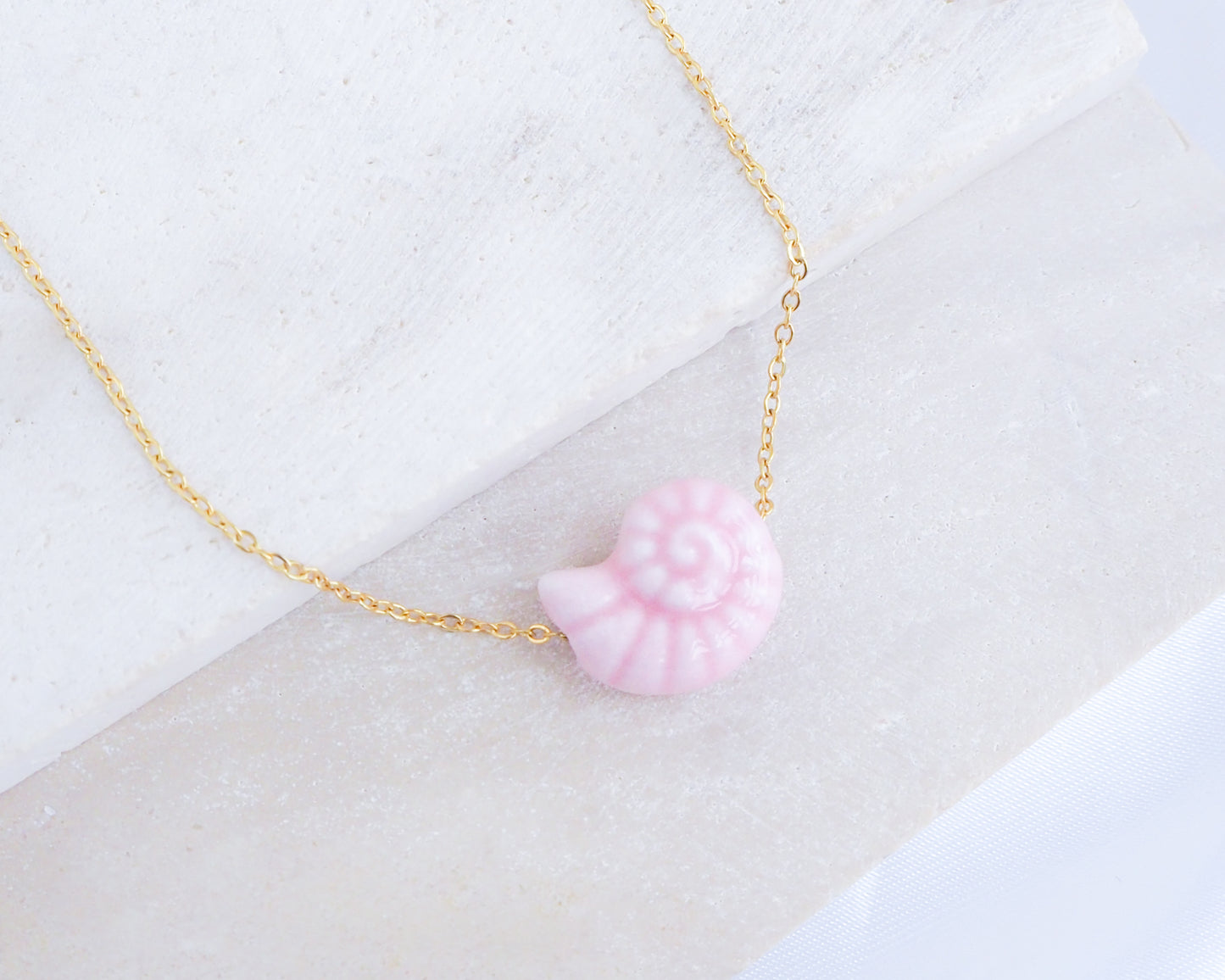 Soft Pink Seashell Ceramic Nautilus Gold Necklace on display