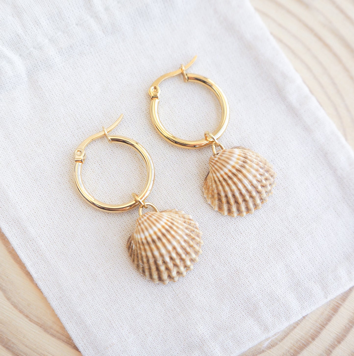Close up of Sunny Mediterranean Cockle Shell Gold Earrings from Portugal displayed on fabric, handpicked yellow cockle shells from Portugal, seabylou, ocean inspired earrings, beach gift