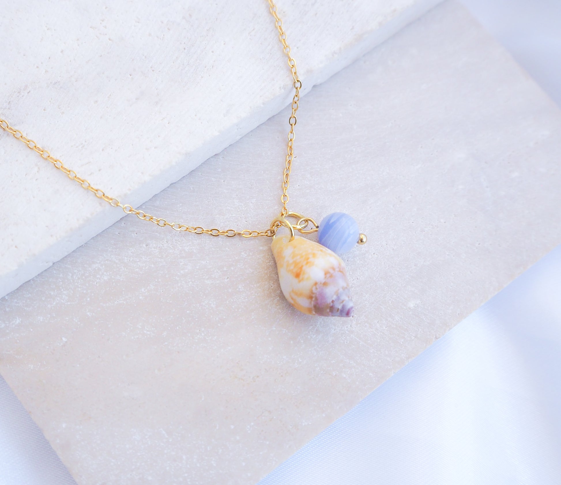 Tiny Light Rustic Dove with Angelite Gemstone Necklace displayed on stone
