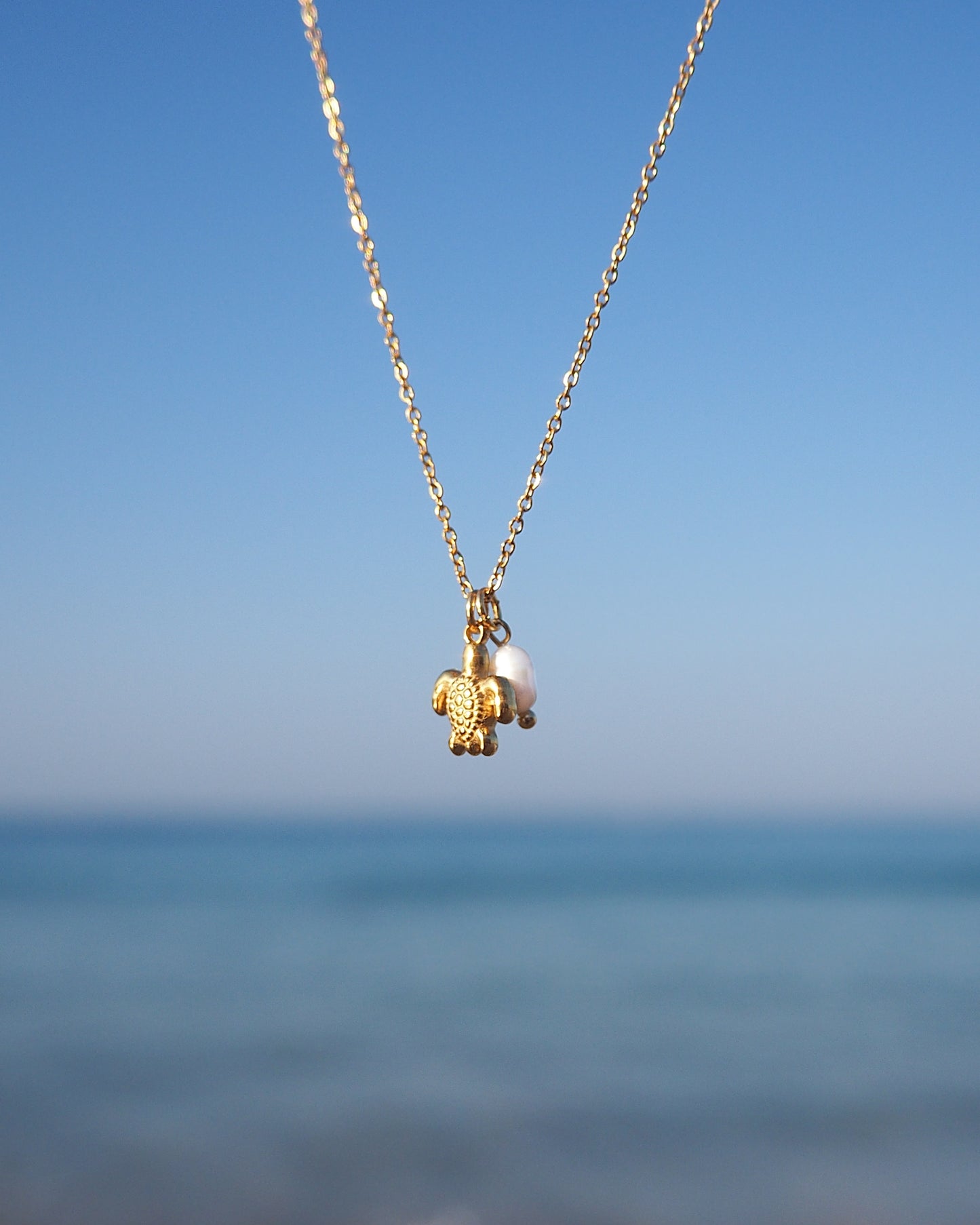 Close up of Tiny Turtle Pearl Necklace with ocean background, Gold Necklace with freshwater pearls and 18k gold turtle pendant, Minimalistic Ocean Inspired Jewelry, Jewelry for Beach Girls