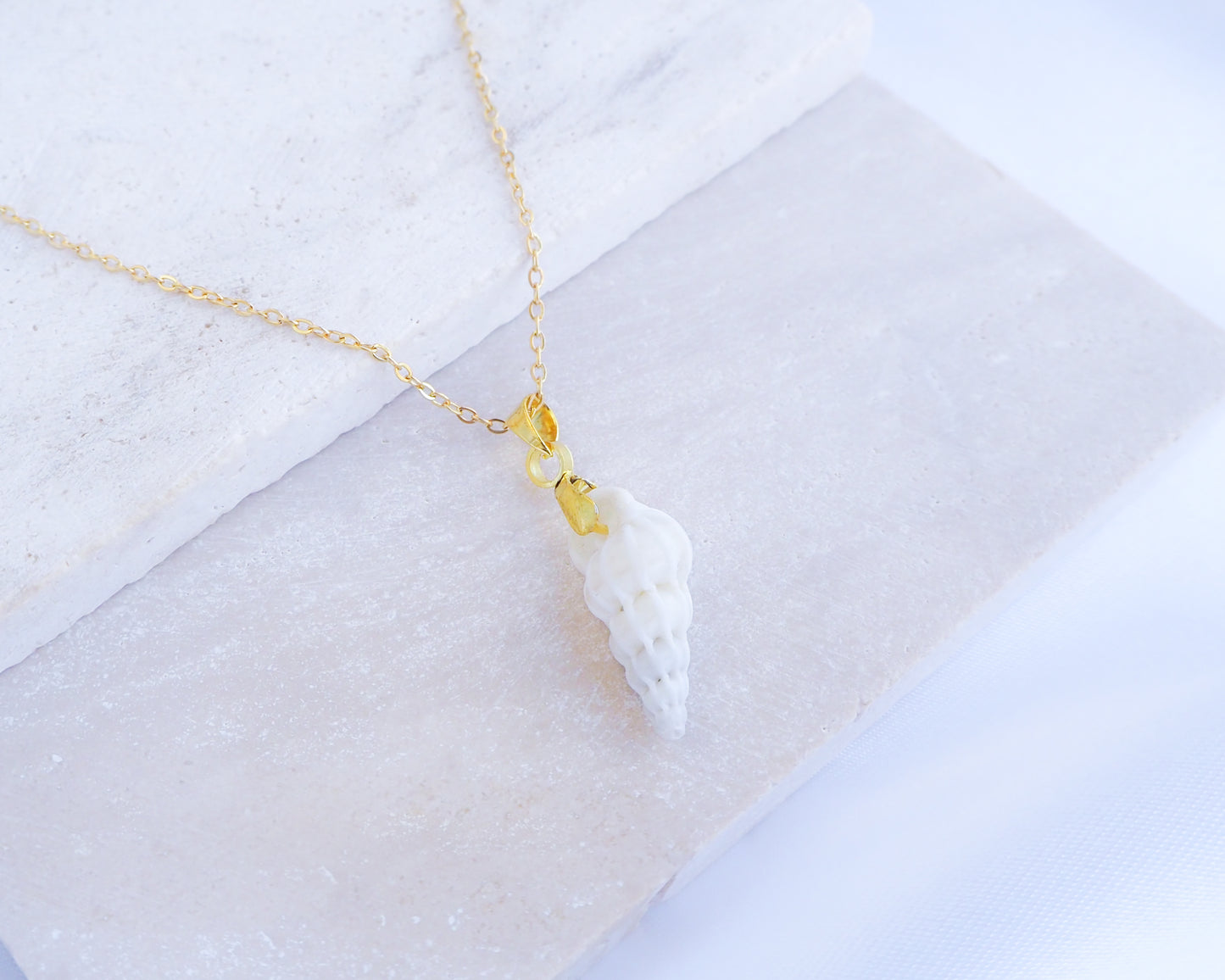 Tiny White Wentletrap Necklace backside displayed on stone