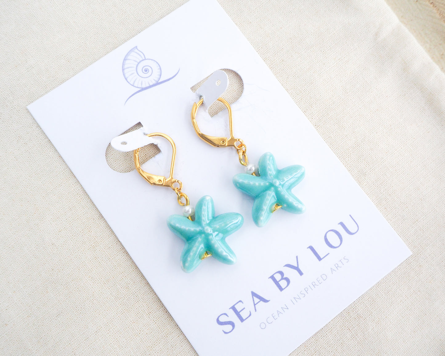 Turquoise Blue Starfish Ceramic Earrings on display