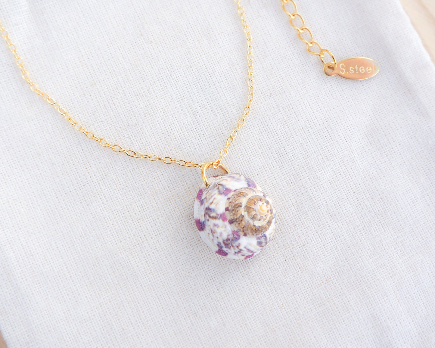 White Fuchsia Magus Top Shell Necklace on display