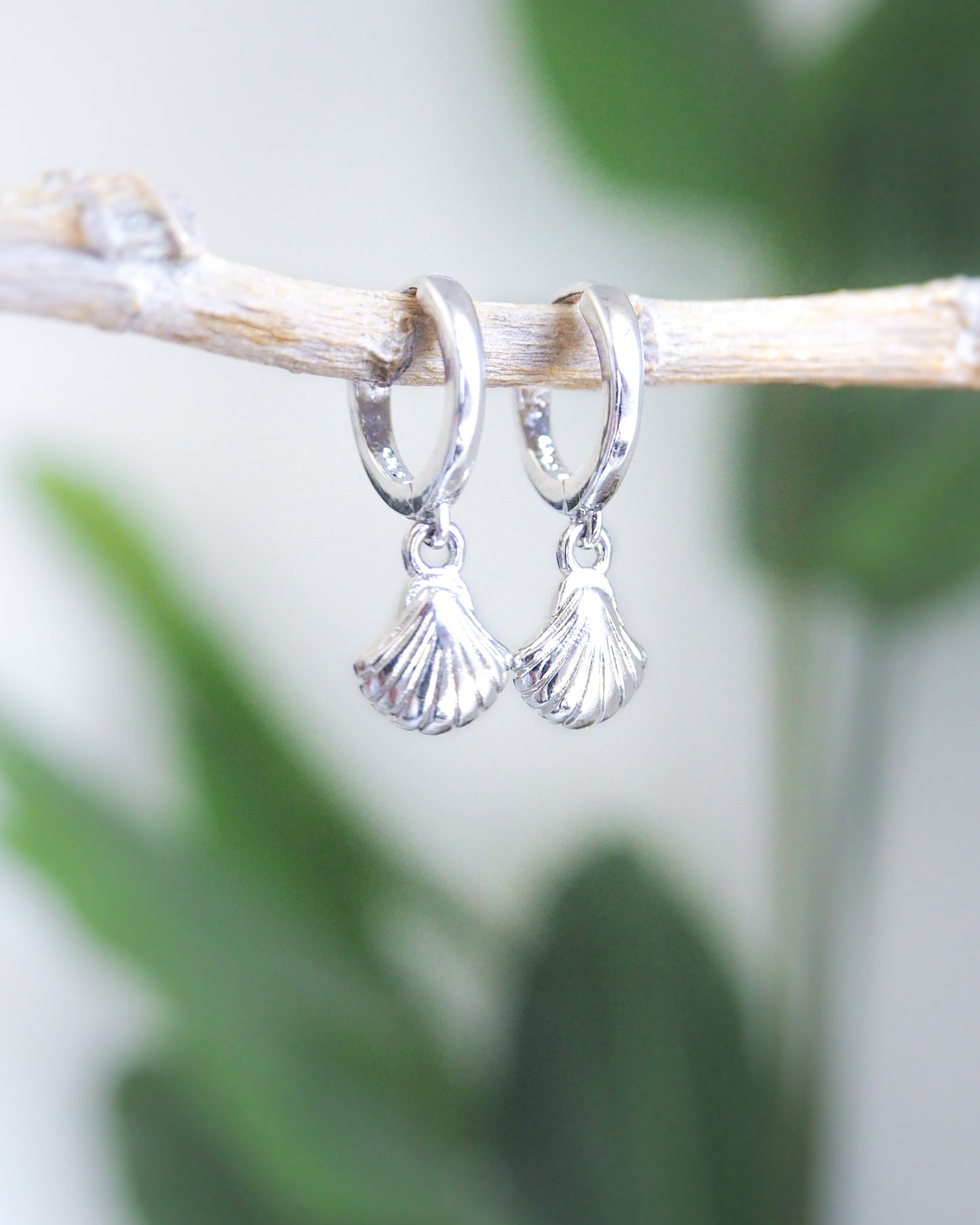 Front view of Silver Tiny Seashell Huggie Earrings with white background and green plant details, 14k gold vermeil or 925 Sterling Silver, Dainty Tiny Scallop Shell Pendant Hoop Earrings, Sea by Lou jewelry, Minimalistic Coastal Style