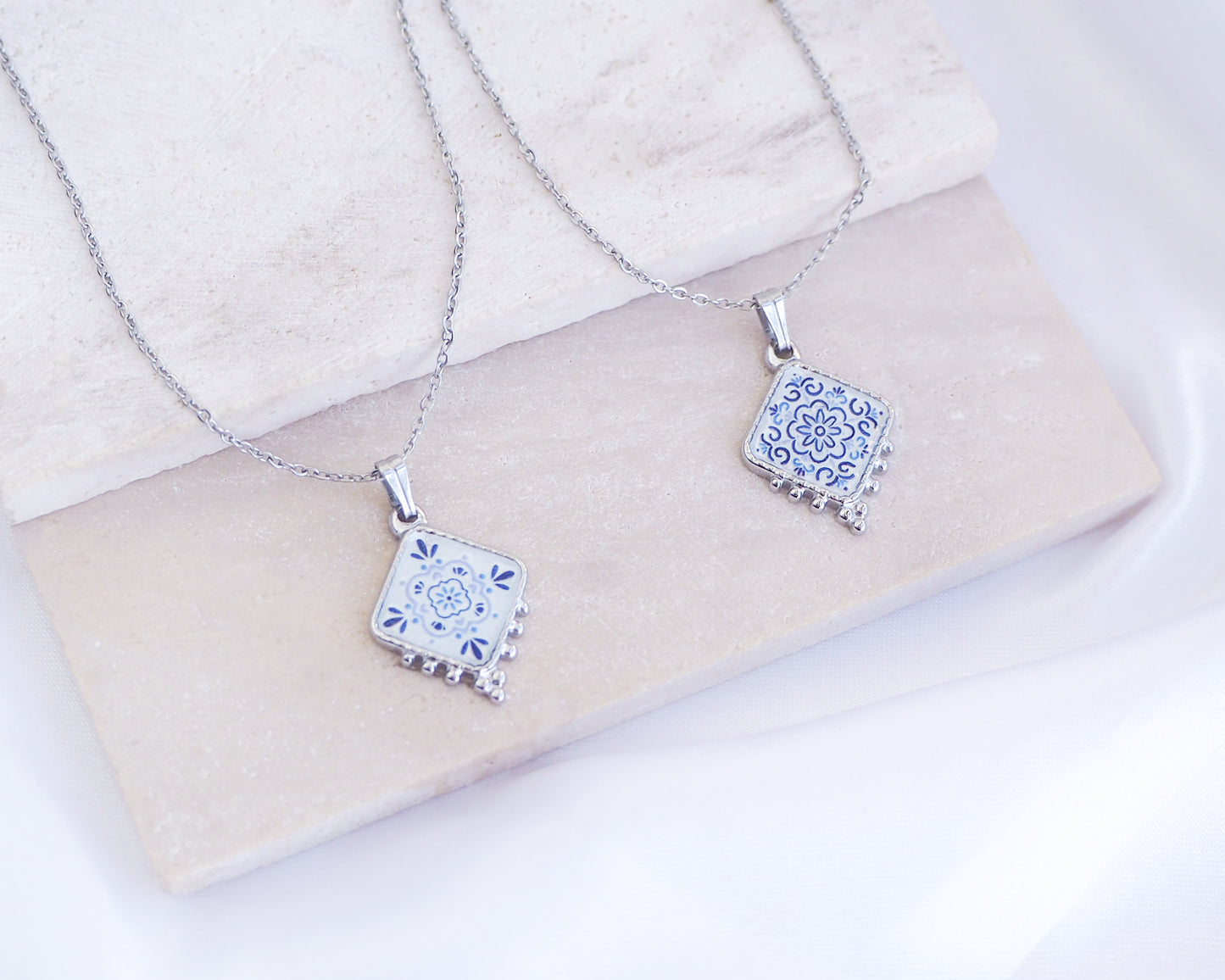 Portuguese Tile Necklace Floral Blue Silver on stone displayed. Made with stainless steel and white blue floral pendant inspired by the Portuguese Azulejo design pattern. 
