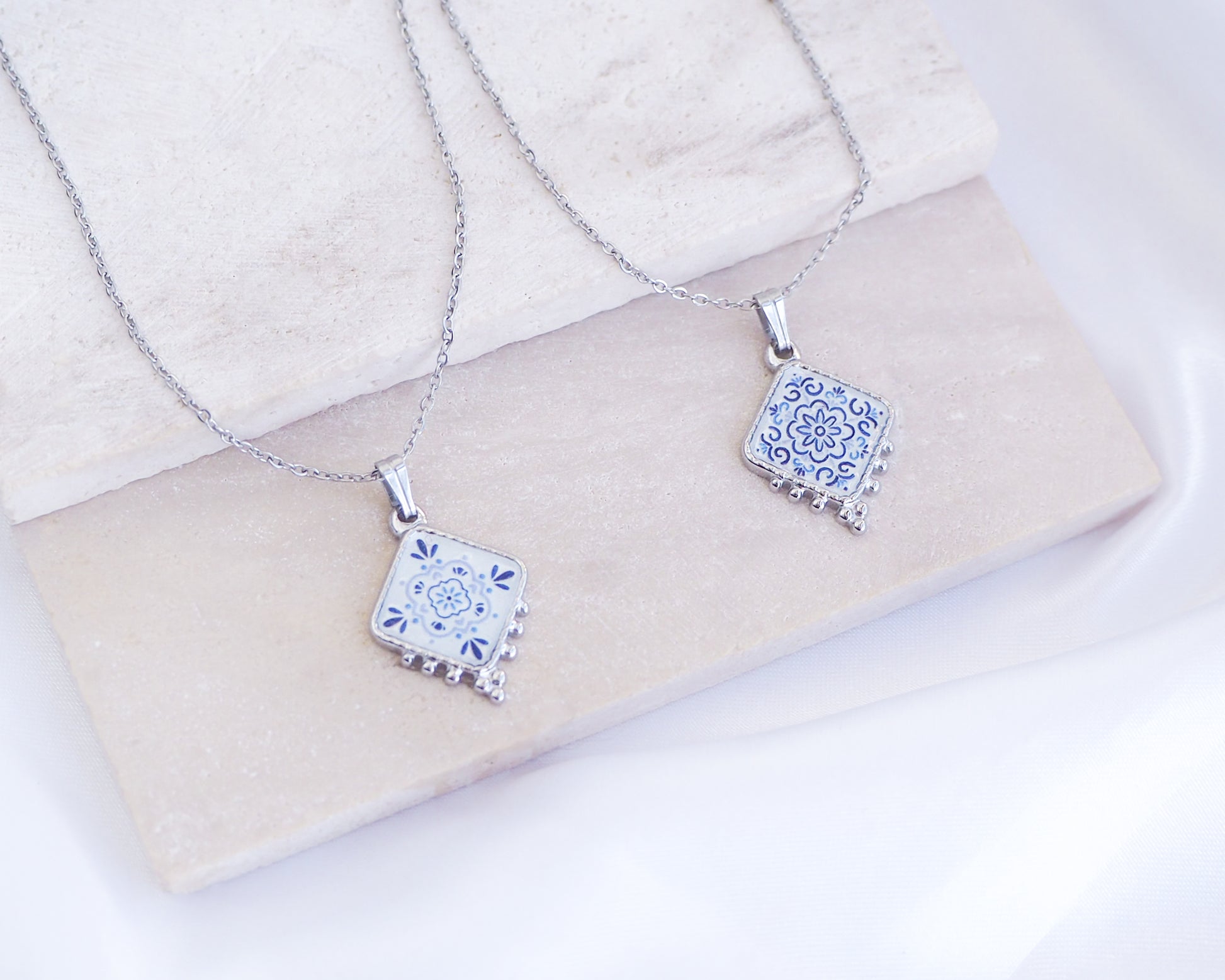 Portuguese Tile Necklace Floral Blue Silver on stone displayed. Made with stainless steel and white blue floral pendant inspired by the Portuguese Azulejo design pattern. 