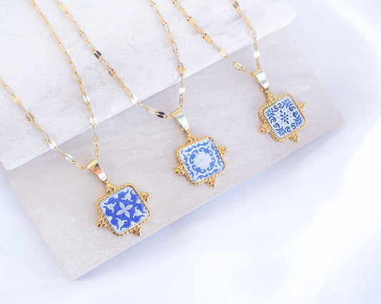 Close up of Gold Portuguese Tile Square Necklaces Blue on stone displayed. Made with 18k gold stainless steel or silver stainless steel and white blue mosaic pendant inspired by the Portuguese Azulejo design pattern. 
